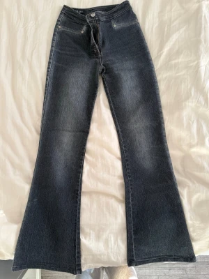 Mörkblå bootcut jeans med detaljer - Ett par högmidjade jeans från märket Hengshun i storlek 7, väldigt bra skick! Köpta utomlands för flera år sedan men använd fåtal gånger. Säljer eftersom dem blivit för små🩷  Innerbens längd: 78cm Från kant till kant i midjan: 35cm