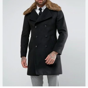 Svart vinterkappa med avtagbar pälskrage i XS. Gianni Feraud - *Mycket fin kappa med avtagbar fuskpälskrage i XS från Gianni Feraud. Knappt använd & är därför i mkt bra skick-nyskick. Fick justera knapparna så att det skulle passa bättre. Kan behöva justeras tillbaka beroende på din preferens.                                                                                                                                                                                      *Ca-Mått i cm: Bröst: 48, Axel: 40, Längd: mätt från mitten 92, Kragens längd: 62.