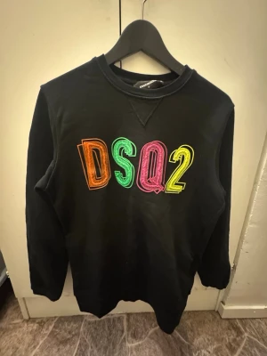 Hoodie  Dsquared2 - Svart sweatshirt från Dsquared2 med färgglad DSQ2-logga framtill. Klassisk modell med rund hals och bekväm passform. Original, med etikett och QR-kod kvar (se bild).
