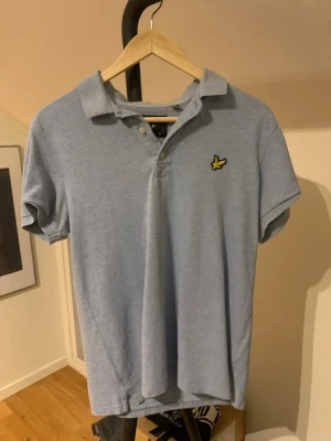 Ljusblå Lyle & Scott piké S - Säljer en ljusblå pikétröja från Lyle & Scott i storlek S. Klassisk krage, korta ärmar och två knappar framtill. Tröjan har den ikoniska gula fågeln broderad på bröstet. Perfekt för dig som gillar stilrena och sportiga plagg. Tröjan har två små fläckar på framsidan men de syns knappast som man ser på bilderna. Hör av dig vid minsta fundering eller fråga och pris kan diskuteras! ✌️💯