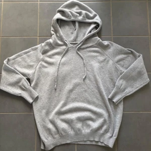 Ljusgrå hoodie med huva och snörning - Skick:Mycket bra.                                  Storlek:158-164/XS.                              Beskrivning:En stilren ljusgrå hoodie med huva och snörning. Tröjan har långa ärmar, ribbade muddar och avslut, samt en relaxed passform. Perfekt för chill dagar eller när du vill ha en enkel och snygg look.Passar perfekt med några snygga jeans.