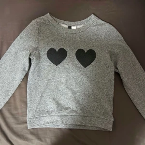 grå tröja  - grå tröja med 2 svarta hjärtor på brösten 