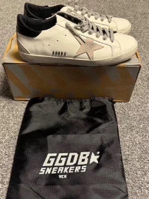 Golden Goose Superstar sneakers vit/svart - Säljer mina golden goose i storlek 42. Säljer pågrund av att dom var försmå för mig skicket är bra. Nypris 5-6000 mitt pris 1200. Tar emot prisförslag så lägg ett 