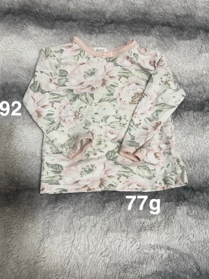 Blommig långärmad pyjamaströja newbie - Supersöt långärmad pyjamaströja från Newbie med blommigt mönster i ljusrosa, beige och grönt. Pyjamaströjan har muddar och rund halsringning med liten rosett. Perfekt för dig som gillar romantisk stil.🌸Fint använt skick. Storlek 92