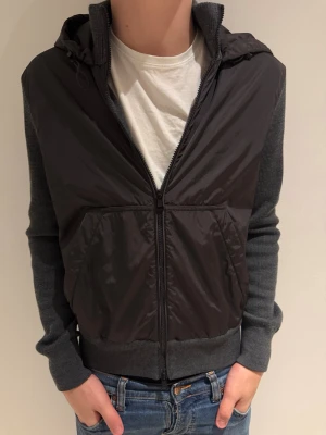 Grå cardigan jacka från Moncler - Säljer en grå cardigan jacka från Moncler med stickade ärmar och rygg samt glansig framsida i syntet. Den är endast använd några gånger så i väldigt fint skick!