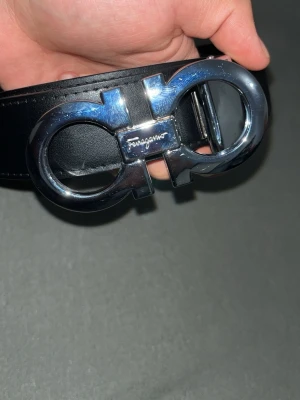 Svart Ferragamo bälte  - Svart ferragamo bälte, helt okej skick alltså den funkar den har två olika sidor jag kan skicka bild privat på den andra.