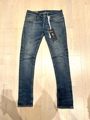 Dondup Jeans - Snygga jeans av märket dondup, prislapp/tag finns med. Storlek 28 men sitter större. Blåa jeans med lite vitt och svart färgstänk. Finns mer bilder! Tveka inte o fråga om det är något!