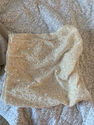 Paljettkjol från Lindex, beige - Säljer en beige kortkjol från Lindex med glittriga paljetter över hela tyget. Kjolen har en mjuk insida och elastisk midja för skön passform. 