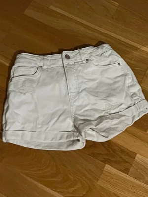 Vita denimshorts från LAB Industries - Snygga vita shorts i denim från LAB Industries med klassisk femficksdesign och uppvikta benslut. Perfekta för varma dagar och enkla att matcha med allt. Stängs med knapp och dragkedja, har bälteshällor och diskreta slitningar framtill som ger en snygg look!