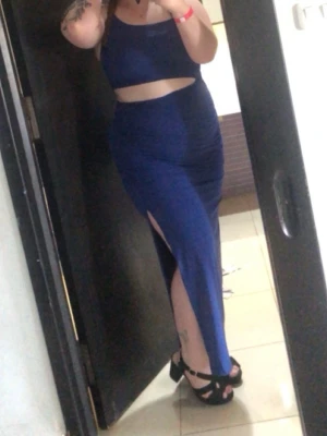 Marinblå långklänning med slits - Snygg marinblå långklänning med smala axelband och oneshoulder-design. Klänningen har en hög slits framtill som ger en cool look. Materialet känns mjukt och stretchigt, troligen polyester. Perfekt för dig som vill sticka ut med en elegant men modern stil.