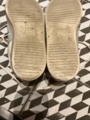 Vita Veja sneakers med grå detalj - Snygga vita sneakers från Veja med grå V-logga på sidan och lila detalj på hälen. Antal små repor, slitet, markeringar, rynkor runt om skorna. speciellt på sidorna, under på botten och V. Stl 36. annars bra skick !!