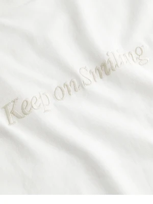 Vit t-shirt med broderad text - Vit oversized t-shirt med broderad text 'Keep on smiling' framtill. T-shirten har korta ärmar och en avslappnad passform, perfekt för en chill look. Tillverkad i mjuk bomull som känns skön mot huden. Original pris 1399