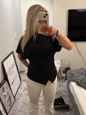 Svart topp med asymmetrisk nederkant - Snygg svart topp med korta ärmar och unik asymmetrisk nederkant. Toppen har en enkel, stilren design och är lätt att matcha med olika outfits. Perfekt för dig som gillar minimalistisk stil. Säljer för den e för stor. Aldrig använd ❤️skriv inna köp!❤️