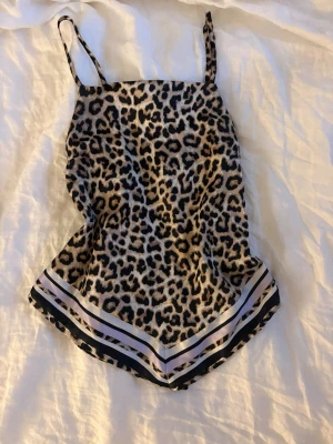 Leopardmönstrat linne med tunna band - Snyggt loungewear-linne med leopardmönster och tunna axelband. Linnet har en lös passform och dekorativa ränder i svart, vitt och rosa längst ner. Perfekt för chill dagar hemma eller mysiga kvällar. Materialet känns mjukt och svalt mot huden.