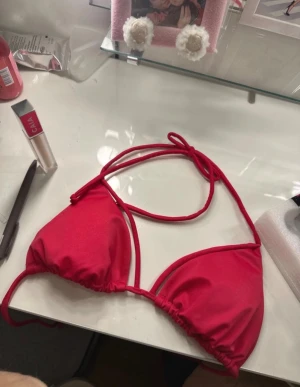 RosaRöd trekantsbikini  - Snygg rosa/röd trekantsbikini/triangelbikini med tunna knytband i nacken och ryggen. Klassisk modell med justerbara kupor och mjukt stretchigt material i 82% polyamid och 18% elastan. Perfekt för stranden eller poolen! Aldrig använd. 