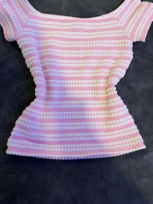 Rosa och vit randig topp från Nelly - Supersöt topp från Nelly i storlek XS med rosa och vita ränder. Toppen har en figurnära passform, korta ärmar och är tillverkad i ett mjukt, strukturerat material. Perfekt för dig som gillar pastelliga färger och en feminin look. 