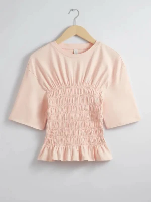 Ljusrosa topp med smock och volang - Supersöt ljusrosa topp med smockad midja och volangkant nedtill. Toppen har korta ärmar och rund halsringning, perfekt för en fräsch och feminin look. Tillverkad i mjuk bomull som känns skön mot huden. Nypris 450. Skriv för fler bilder!