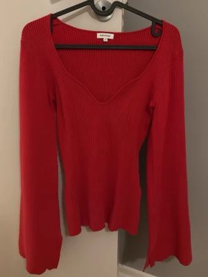 Röd ribbad topp från Bubbleroom - Trendig röd topp med ribbad struktur och v-ringad hals. Toppen har långa, lätt utsvängda ärmar och sitter snyggt figurnära. Perfekt för dig som vill ha en enkel men ändå statement topp i garderoben.