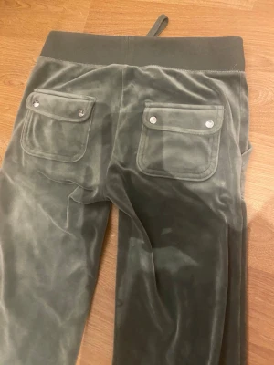 Grå mjukisbyxor i velour med fickor - Äkta gröna juicy couture byxor, perfekt för en mysig kväll, rekommenderar starkt för soffpotatisar som älskar att ha på sig skönt material.