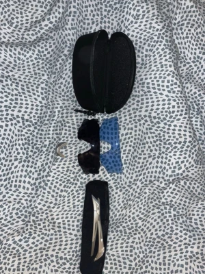 Sportiga solglasögon med silverbågar - Säljer ett par sportiga solglasögon med silvriga metallbågar och utbytbara linser i svart och blått. Glasögonen har en näskudde i vitt och kommer med ett hårt svart sopfodral. Perfekta för dig som vill ha en cool och funktionell look.