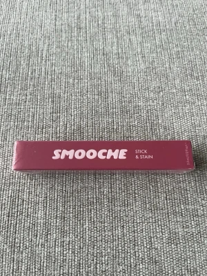 Smooche Stick & Stain Watermelon Sugar - Snyggt läppstift från Smooche i nyansen Watermelon Sugar. Förpackningen är rosa med vit text och läppstiftet är i stickform. Perfekt för dig som vill ha en fräsch och somrig färg på läpparna. Materialet är klassisk plastförpackning.