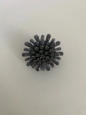 Statementring i svart/silvrig metall - Cool statementring i svart metall med unik blomliknande design. Ringen har utstickande detaljer och små glittrande stenar som ger en edgy och trendig look. Perfekt för dig som vill sticka ut och addera något extra till din outfit.