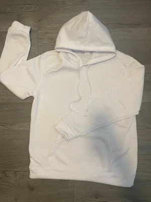 Vit hoodie med magficka och huva - Mjuk och snygg vit hoodie med 100% polyester  i storlek Large med huva och praktisk magficka. Skön passform och stilren design som passar lika bra till vardags som till avslappnade tillfällen. En bekväm favorit i garderoben.✨