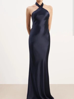 Balklänning marinblå - Helt ny aldrig använd marinblå balklänning i satin storlek S. Köpt i London. Halterneck med en fin hög skurning fram samt låg rygg som ger en exklusiv känsla. Lapparna finns kvar. Perfekt för dig som vill ha en unik och exklusiv balklänning till studenten