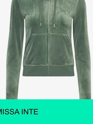 Grön velour hoodie från Juicy Couture - Snygg grön hoodie i mjuk velour från Juicy Couture. Dragkedja framtill, två fickor och justerbar huva med snören. Ikonisk JC-logga broderad på bröstet. Perfekt för en chill och trendig look.