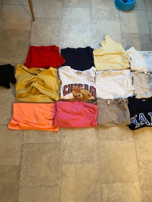  t-shirts och toppar i olika stilar - Säljer ett gäng t-shirts i olika färger och modeller, bland annat röd, marinblå, gul, vit, grå, rosa och orange. Några har tryck, som Chicago och Yale, och alla är kortärmade. Perfekta för dig som vill ha variation i garderoben. Går att köpa separat också!