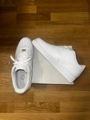 Nike Air Force 1 Low ‘07 White - Säljer ett par Nike Air Force 1 Low ’07 White i helt nytt och oanvänt skick. Inga märkek, inga skavanker och inga konstigheter utan helt fräscha skor direkt ur sko lådan som aldrig har använts ute!!  Dessa vita Airforce är en sko som går att använda året runt och passar till allting,  perfekt om du vill unna dig ett par nya skor eller om du letar efter en riktigt bra julklapp!!  (Orginalbox medföljer!) 