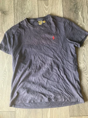 Mörkblå t-shirt Polo Ralph Lauren - Snygg mörkblå t-shirt från Polo Ralph Lauren i bomull med röd broderad logga på bröstet. Modellen är custom slim fit med rund hals och korta ärmar. Perfekt för dig som gillar klassisk stil med en modern touch.