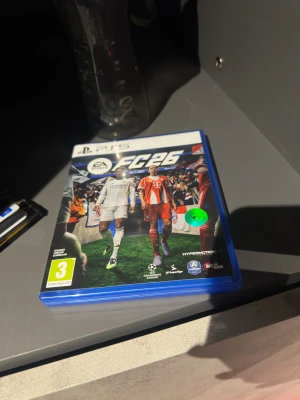 EA Sports FC 26 PS5 - EA Sports FC 26 till PlayStation 5. Fysiskt exemplar med originalfodral och skiva i mycket gott skick. Upplev den senaste fotbollssäsongen med nya lag, spelare och HyperMotionV-teknik. Perfekt för dig som vill spela Champions League och Ultimate Team.