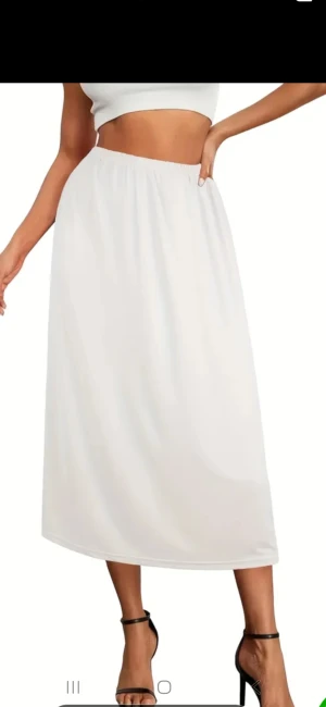 Underkjol  - Snygg vit långkjol med enkel och clean design. Kjolen har resår i midjan för skön passform och är gjord i ett lätt material som ger ett flowigt intryck. Perfekt för dig som gillar minimalistisk stil och vill ha en kjol som är lätt att matcha.