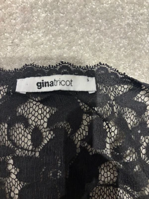 Svart spetsblus från Gina Tricot - Säljer en svart blus från Gina Tricot i storlek S. Blusen är helspets med blommigt mönster och har korta ärmar. Den är genomskinlig och har en rundad halsringning. Perfekt för dig som gillar detaljer och vill sticka ut lite extra.