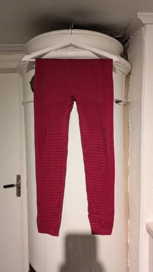 Vinröda ribbade leggings träningsbyxor - Snygga vinröda leggings med ribbade detaljer längs benen och diskreta meshpartier. Stretchigt material som sitter tight och följer kroppen. Perfekta för dig som gillar att sticka ut med färg och mönster.