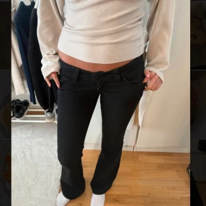 Svarta bootcut jeans låg midja - Snygga svarta jeans med låg midja och bootcut-ben. Klassisk femficksmodell med knapp och dragkedja framtill. Jeansen har en rak passform över låren och lätt utsvängda ben, vilket ger en cool siluett. Perfekta för dig som gillar en tidlös och trendig look.
