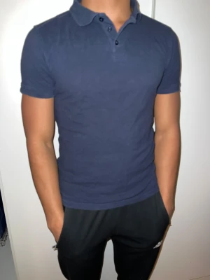 Marinblå och grå polotopp herr - Två stilrena polotoppar i marinblått och ljusgrått, båda med klassisk krage och korta ärmar. Slim S passform som sitter snyggt mot kroppen. Perfekt för dig som gillar enkel och clean stil. Båda ingår med pris.