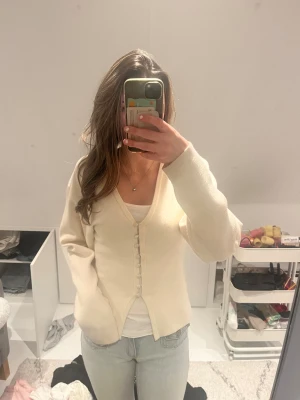Beige kofta från Gina Tricot XS - Superfin beige kofta från Gina Tricot i storlek XS. Koftan har v-ringning, långa ärmar och snygga knappar framtill. Materialet är mjukt och stickat, perfekt för lager på lager. Passformen är normal och den är enkel att matcha med jeans eller kjol.