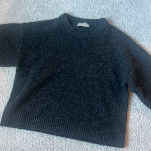Mörkgrå stickad tröja  - Mysig mörkgrå stickad tröja från Neo noir med rund halsringning och ribbade muddar. Perfekt för kyliga dagar och enkel att matcha med olika outfits.
