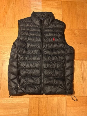 Svart dunväst från Polo Ralph Lauren - Svart Ralph Lauren polo väst. Sparsamt använd. Inga repor eller hål. Storlek M