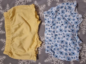 Två shorts från Lupilu, blommiga & gula - Säljer två gulliga shorts från Lupilu i storlek 62/68. Ena paret är ljusgula med volangkant och resår i midjan, andra är vita med blått blommönster och samma volangdetalj. Båda är i mjuk bomull, perfekta för varma dagar och chill stunder.