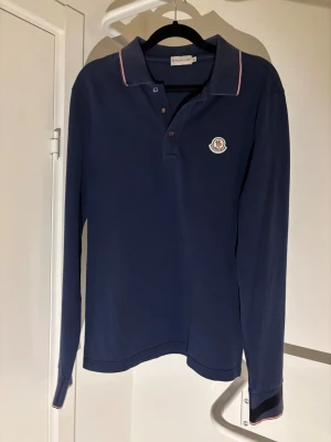 Marinblå pikétröja från Moncler - Jag säljer nu en riktigt stilren moncler piké i storlek M men sitter mer som en S. Tröjan är gjord av bomull. Skick 8/10 Inga defekter så som hål eller liknande. Kort sagt en riktigt snygg tröja. Kontakta mig om du skulle ha frågor ;)