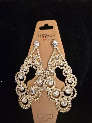 Glittrande örhängen  - Bilden visar ett par stora glittriga örhängen med strass och guldfärgade detaljer, men ingen väst finns med.