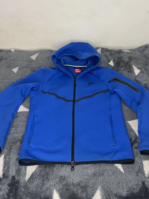 Nike Tech Fleece - Säljer min blåa Nike Tech Tracksuit då jag inte använder den så ofta, byxorna är i storlek S och där koftan är XS. Har använt dressen 2 gånger och köpte den för 2250- i butik.