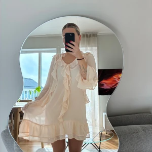 Volangklänning från Kappahl - Superfin ljus kortklänning från Kappahl med volanger längs halsringningen och framtill. Stor i storlek. Använd vid ett tillfälle 