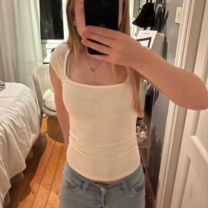 Vit linnetopp från Gina Tricot - Säljer en stilren vit linnetopp från Gina Tricot med fyrkantig ringning och breda axelband. Toppen är figurnära och har en enkel, clean look som passar perfekt till jeans eller kjol. Aldrig använd 💓