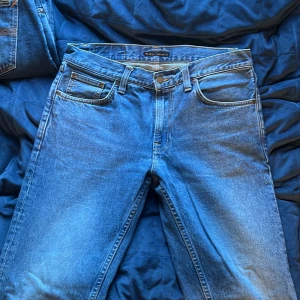 Nudie Jeans Gritty Jackson blå jeans - Säljer ett par Nudie Jeans Gritty Jackson i modellen Day Dreamer. Klassiska blå jeans med raka ben, fem fickor och snygga kontrastsömmar. Tillverkade i 100% bomull för en autentisk jeanskänsla. Perfekta för dig som gillar en tidlös och clean look.