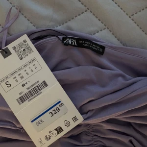 Ljuslila långklänning från Zara - Pris går att diskuteras! Supersnygg långklänning från Zara i en ljuslila nyans. Klänningen har rynkade detaljer över byst och midja och en figurnära passform. Tillverkad i ett mjukt, glansigt material som känns lyxigt och trendigt. Säljes pga att den ej kommit till användning 