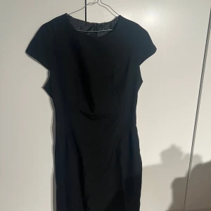 Svart kort klänning från Zara Basic - En stilren svart klänning från Zara Basic med kort ärm och figurnära passform. Klänningen har rund halsringning och dragkedja i ryggen. Perfekt för dig som gillar en klassisk look med enkel design.